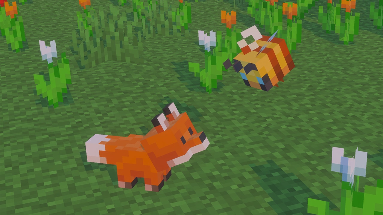 Close-up of an orange baby fox in green grass looking up at a baby bee flying above. White and orange flowers surround them. 