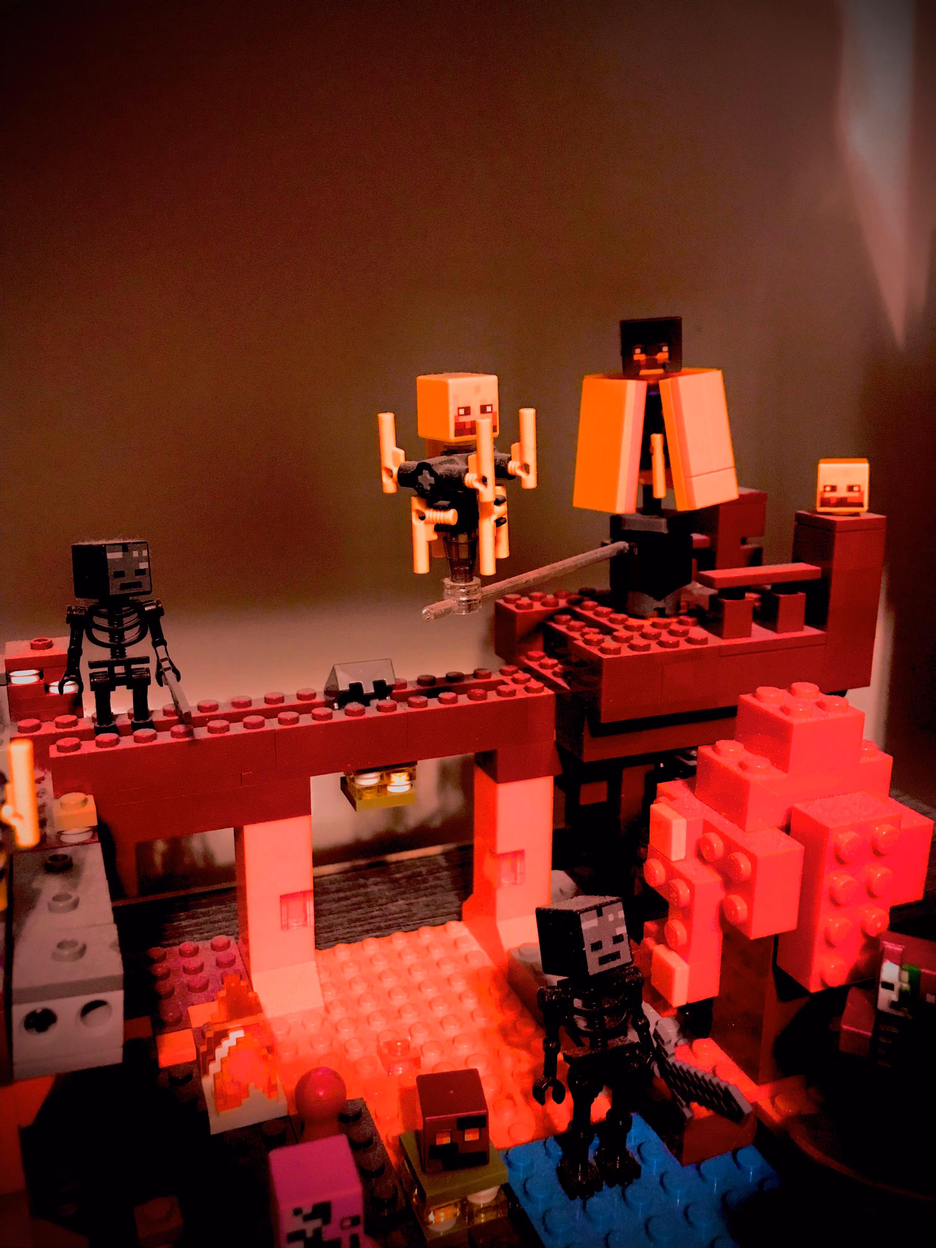 Photo of a level from Minecraft Dungeons recreated using LEGO. There are white and dark brown pieces making up the walkways and floors, and the second level has a few skeleton mobs hanging around while a ministrosity dangles from the edge between tiles. 