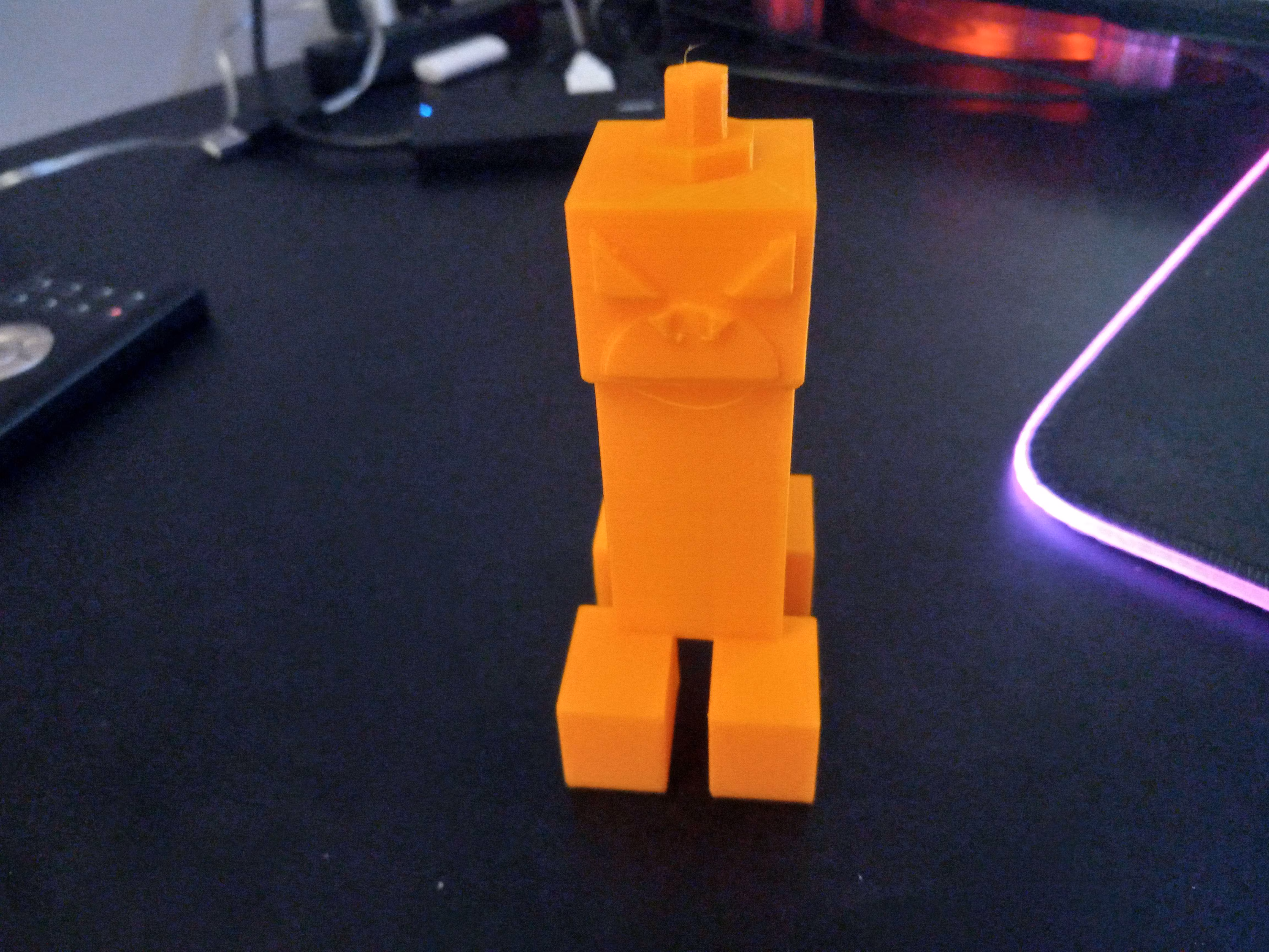 Photo of a 3D printed orange creeper from Minecraft with a jack-o-lantern for a head