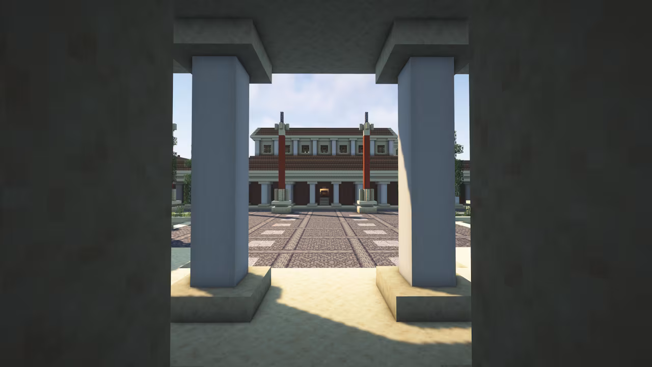 Minecraft map view framed by stone pillars, looking across a tiled courtyard toward a symmetrical, classical-style building with columns and red banners in bright daylight.