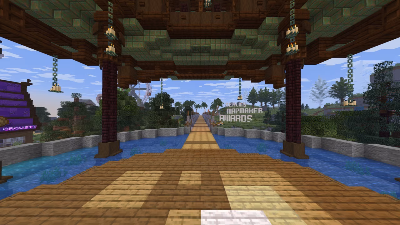 A Minecraft map screenshot of a wooden pavilion overlooking a water-lined bridge leading into a lush landscape, with hanging lanterns and a distant sign reading “Mapmaker Awards.”