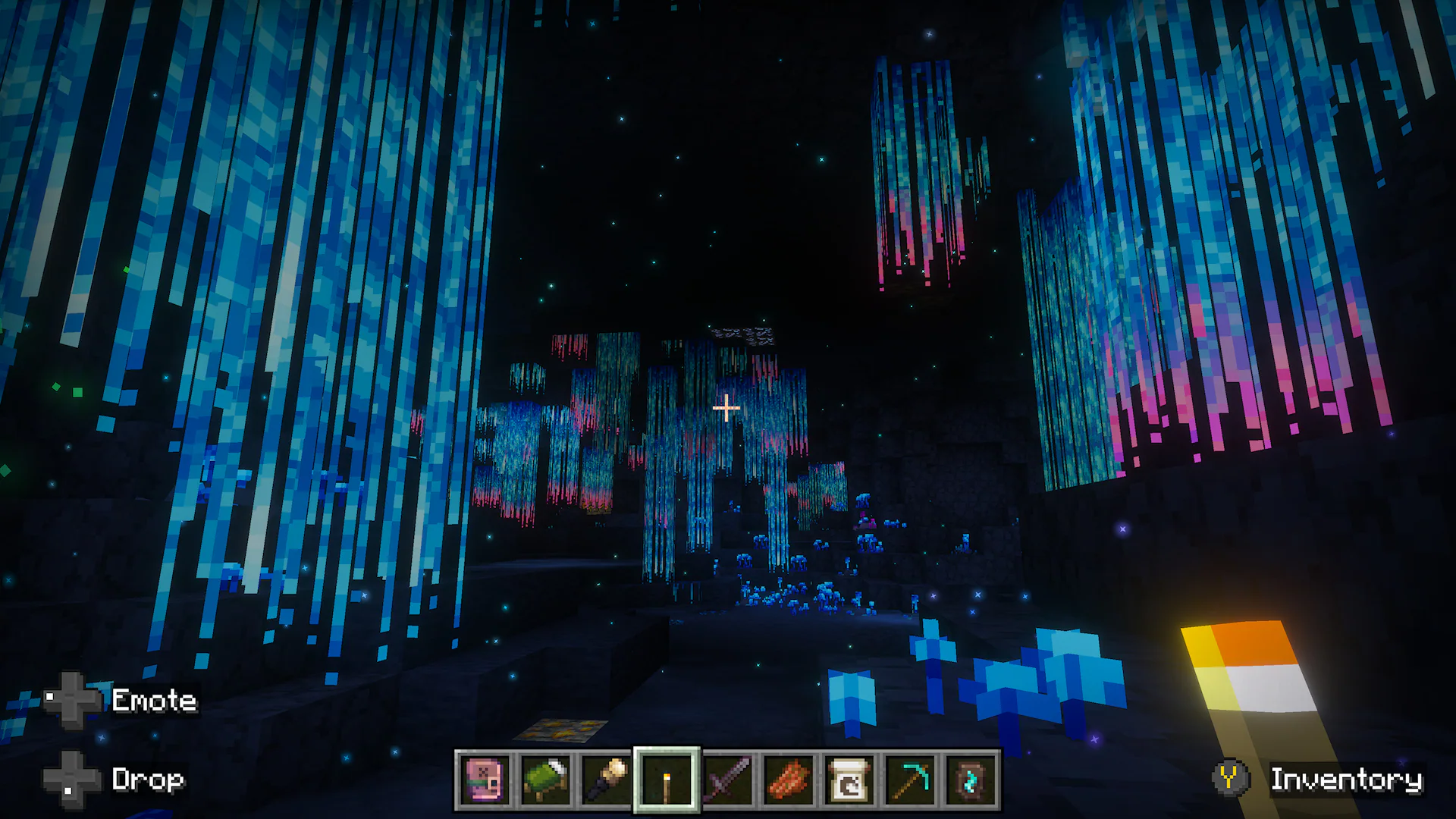 Minecraft player explores a dark cavern illuminated by hanging blue and pink glowing plants and scattered blue vegetation.