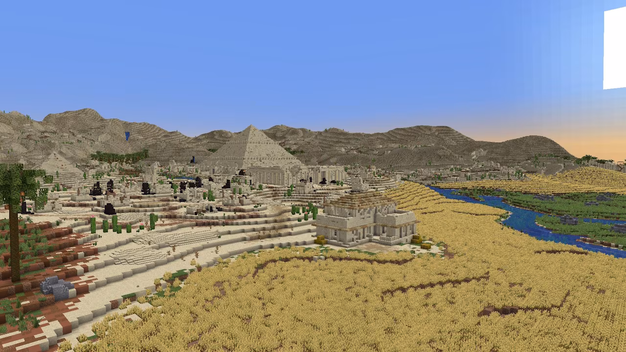 A Minecraft screenshot, depiciting a pyramid surrounded by a village, with a mountainrange in the background and a river running next to the village.