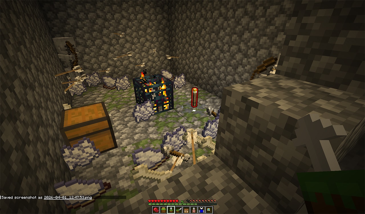 A variety of items strewn on the ground inside a cave and two skeletons. There is a spawner in the middle of the cavern